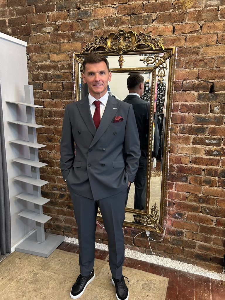 Customer wearing a charcoal double-breasted suit with a burgundy tie in the boutique.
