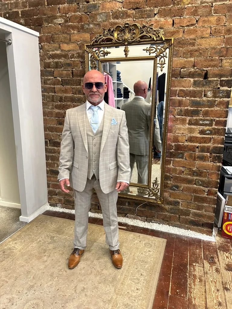 Customer wearing a light checked three-piece suit, pale blue tie and brown shoes in the boutique.