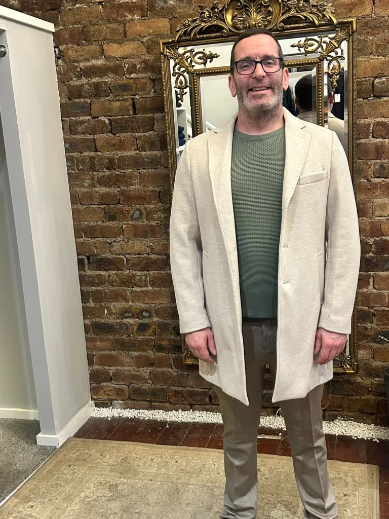 Customer wearing a cream blazer and green knitwear in the boutique.