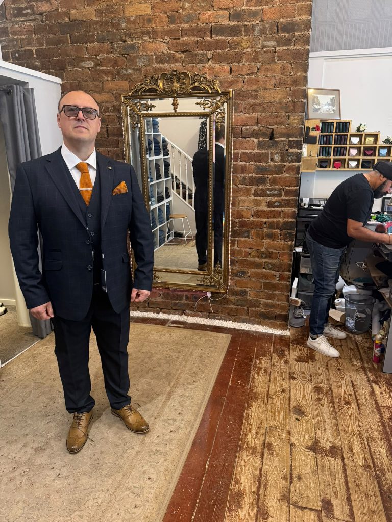 Customer wearing a dark checked suit with a gold tie and pocket square.