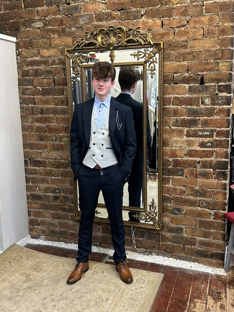 Customer wearing a navy suit with a light checked waistcoat and brown shoes.