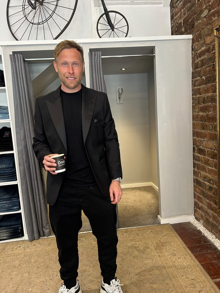 Customer wearing a black jacket and top with light trainers beside the fitting rooms.