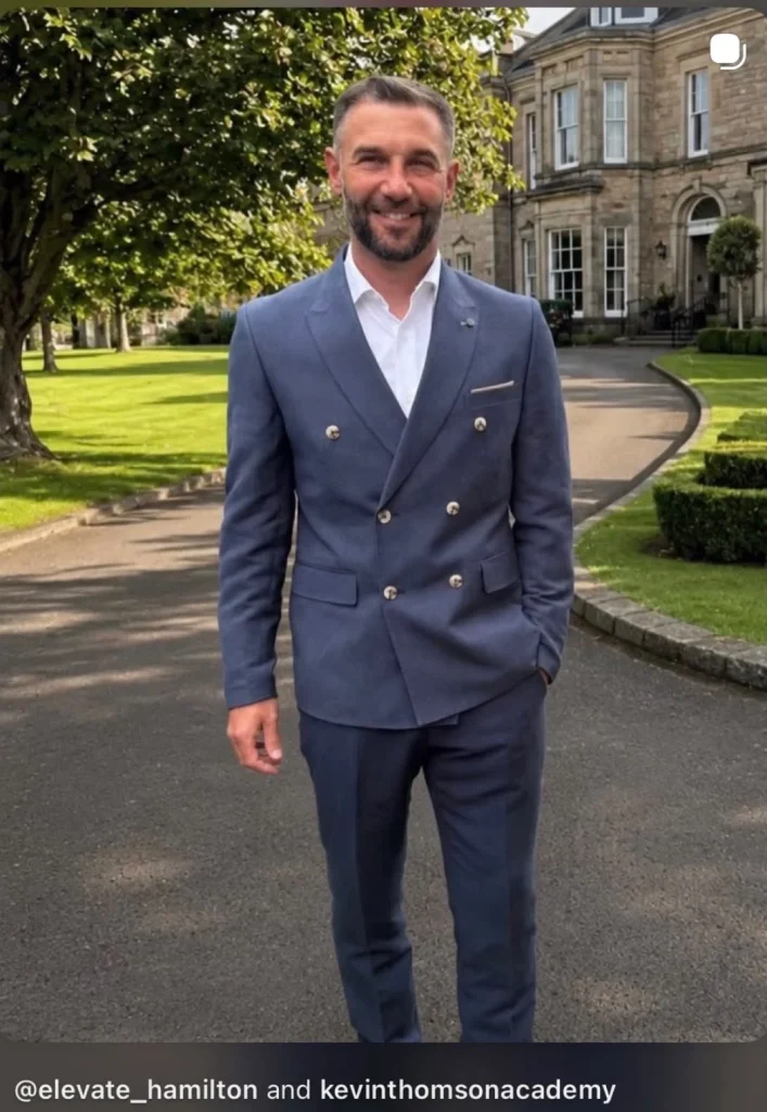 Guest wearing a blue double-breasted suit and white shirt outdoors.