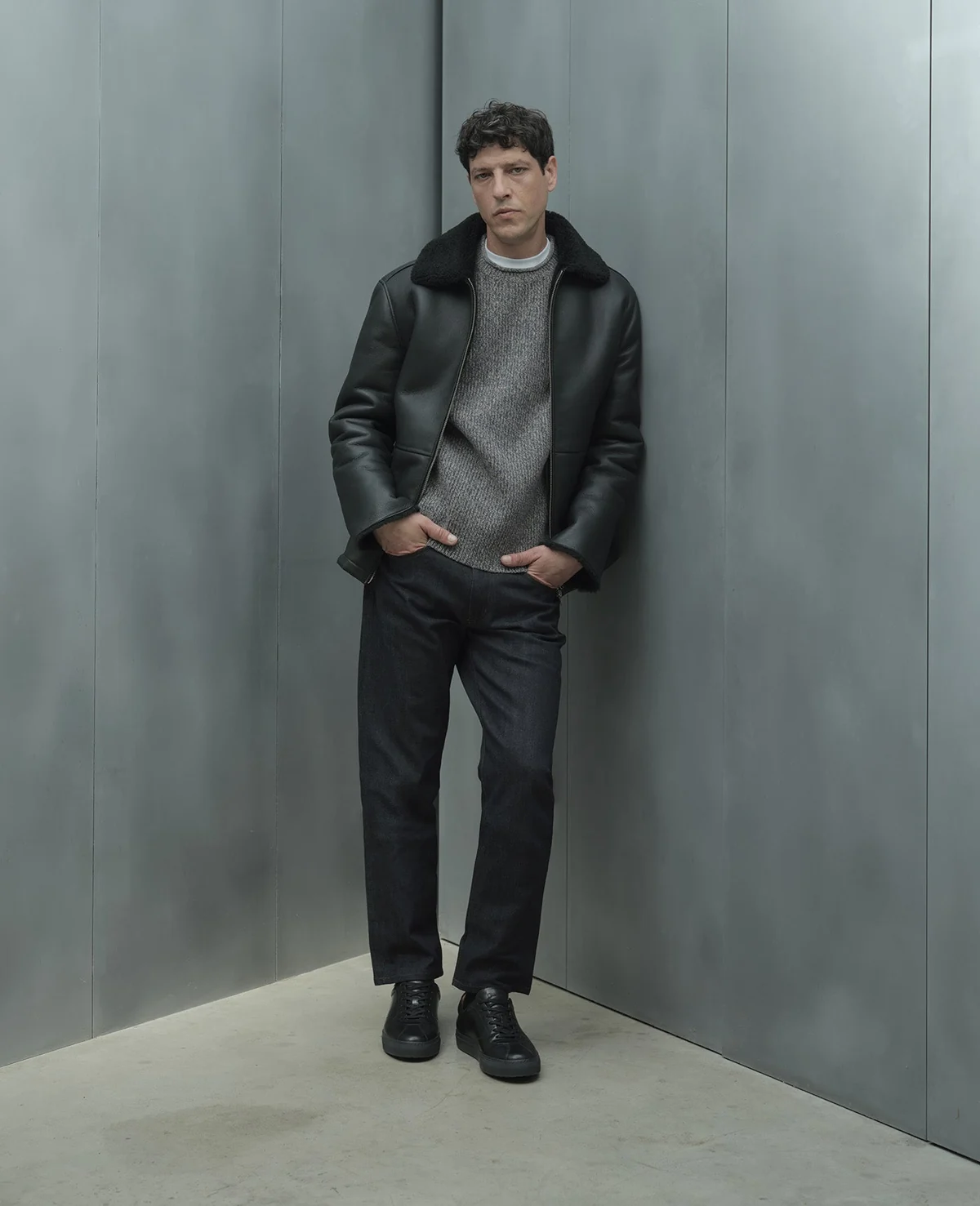 Dark jacket worn over a grey knit with dark trousers
