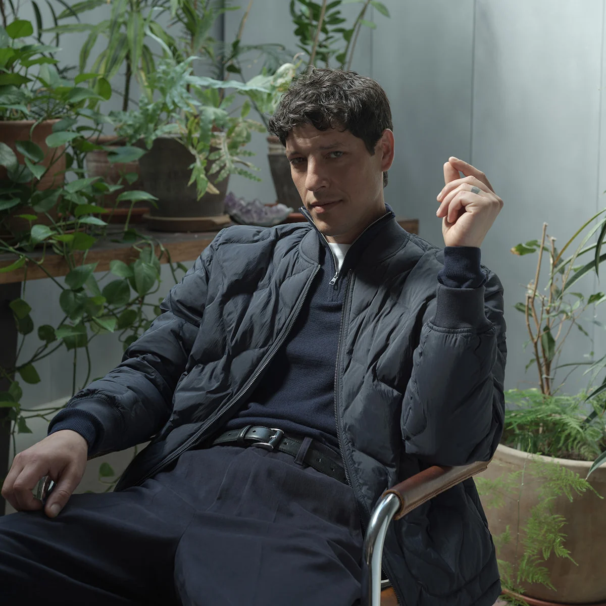 Model wearing dark Oliver Sweeney layers seated among plants