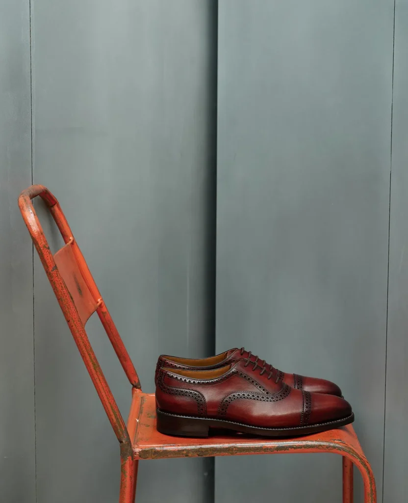 Brown leather brogue shoes on an orange chair